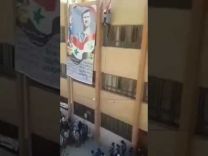 بالفيديو : لحظة سقوط طالب سوري موالي للنظام ميتاً أثناء رفع العلم فوق صورة بشار