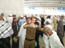 يساعد حاج كبير السن  في رمي الجمرات أثناء الحج‎